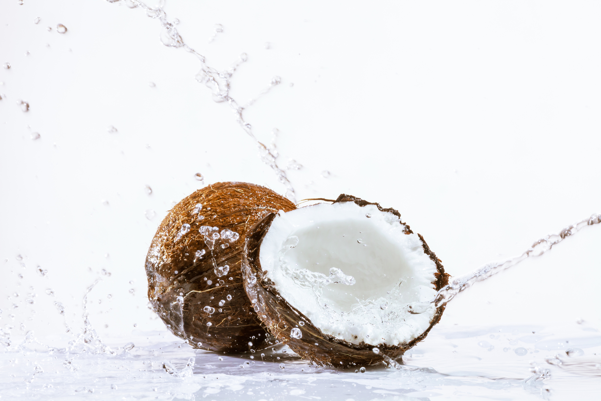 cracked coconut with big splash, isolated on white